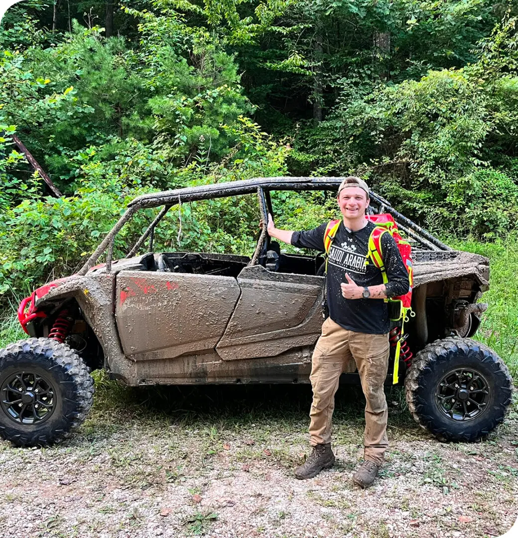 A man standing next to an off road vehicle.