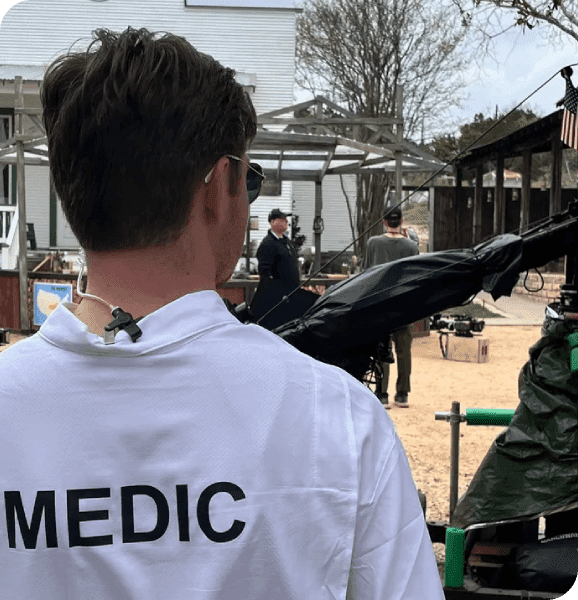 Medic on film set with crew nearby.